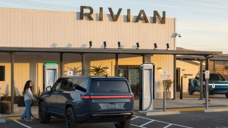 Rivian electric SUV charging outside Rivian service center with large signage